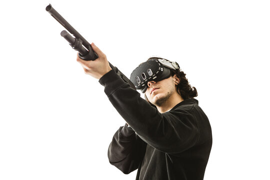 Man wearing virtual reality headset aiming shotgun controller in VR shooting simulation