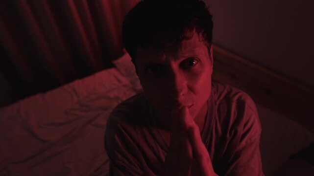 Desperate man praying and pleading with God while looking directly into the camera, creating a direct address feeling of confession, faith and spiritual crisis in dramatic red low key light
