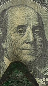 Dollar Bill with Benjamin Franklin Burns on Green Screen. Burning Benjamin Franklin portrait chars against green screen. Growing flame consumes banknote leaving dark uneven burned surface.