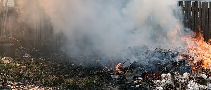 Smoldering debris and smoke rising from backyard fire