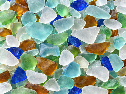 Full-frame arrangement of softened sea-glass fragments in pale aqua, frosted white, mint, amber, and cobalt, rounded edges