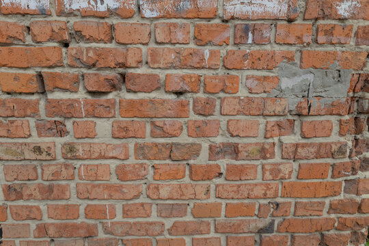 Old weathered red brick wall texture with concrete patch and grunge cement mortar. Vintage industrial background surface for architectural design, urban abstract patterns and aged historical structure