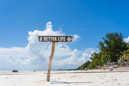 A Better Life sign on tropical beach. Wooden arrow pointer with A Better Life words on white sand coast. Concept of future goals, dreams, career path, relocation and lifestyle choice