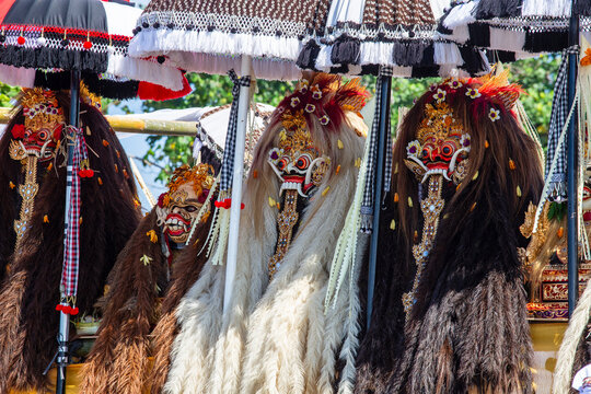 Traditional Balinese Barong masks and umbrellas during ritual ceremony, close up. Group of sacred Barong costumes with mythical masks and ceremonial umbrellas in Bali, Indonesia