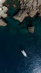 Aerial view of a yacht or boat in green sea by the coast with rocks © raeva