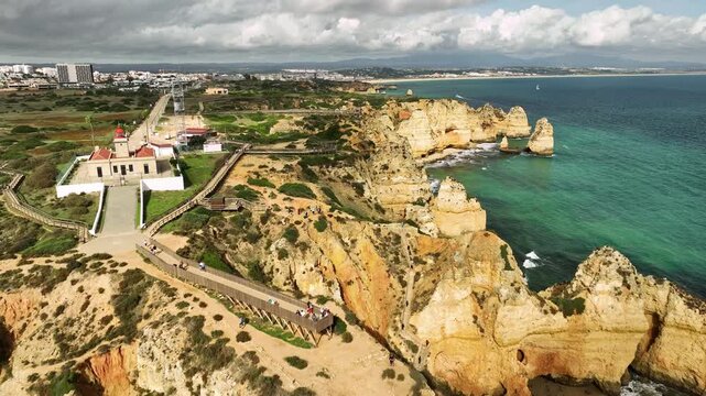 Drone view of Ponta da Piedade in Lagos, Algarve, Portugal, with ocean cliffs, shore rocks and sea stacks. Pull away retreat dolly shot.