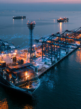 Aerial view of illuminated shipping port with cranes