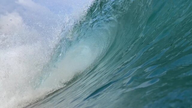 Close up view of clean ocean surfing wave barrel curling with white foam spray in tropical sea. Perfect background for surfing, water sports, and extreme adventure.