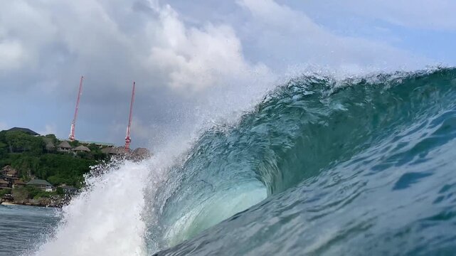 Pure marine landscape showing pristine turquoise ocean wave curling under cloudy blue sky. Concept of ocean ecology, natural energy, and tropical climate beauty