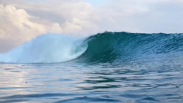 Dynamic action shot of ocean swell forming hollow wave tube with white splash in clear water. Ideal visual asset for nature documentaries, commercial, and promo.