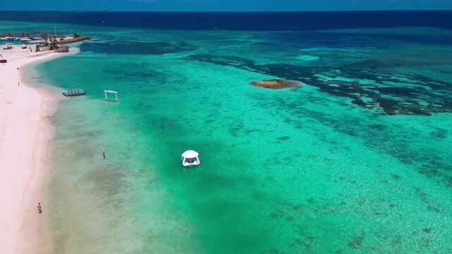 Aerial turquoise lagoon and white sand, floating gazebo in shallow clear water near coral patches, remote island shoreline, calm tropical atmosphere, drone panorama over maldives, Male