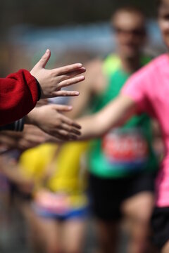 High-Five Between a Child and a Marathon Runner Along the Race Route