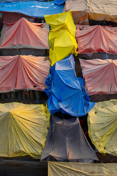 Vertical view of tents covered with yellow blue and pink tarpaulins packed together at the Maha Kumbh Mela camp, Prayagraj, India