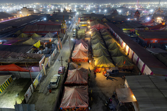 Aerial view of the illuminated Maha Kumbh Mela tent city at night with lit temples cars and rows of tents, Prayagraj, India
