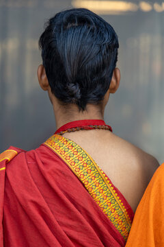 Back view of a young man with wet dark hair a rudraksha necklace and a red cloth with a patterned border, Prayagraj, India
