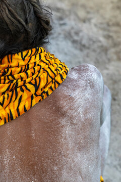 Close-up of the ash covered back of a Naga Sadhu with matted hair and a tiger print scarf at the Maha Kumbh Mela, Prayagraj, India