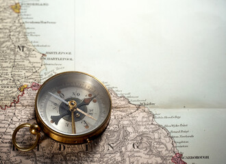 Vintage brass compass on an old England geographic map.  Antique navigation instrument for travel, exploration, geography and discovery concept.  © Tryfonov