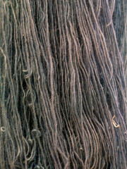 Close-up detailed abstract background of textured dark blue or grey natural wool yarn fibers hanging vertically. © fornax