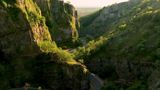 Drone flying backward through a dramatic rocky green gorge, England