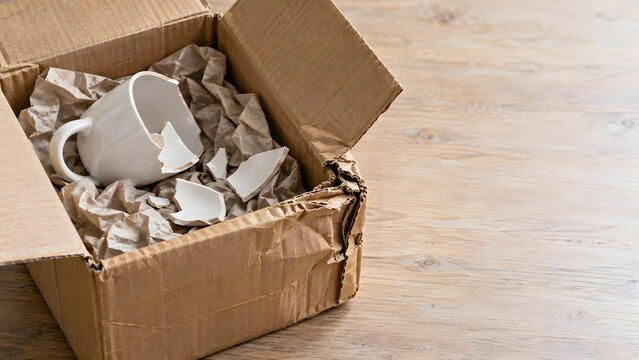 Damaged cardboard delivery box with broken ceramic mug