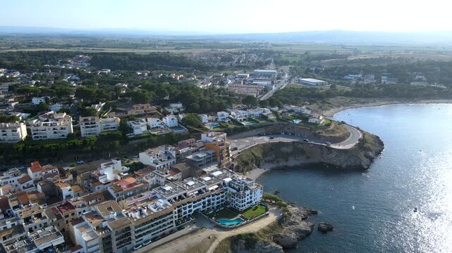 Front aerial view approaching L'Escala town center from the clear sea bay. Travel landscape of Costa Brava, Girona, Catalonia, Spain