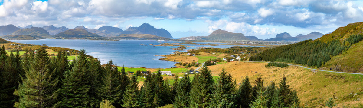 Panoramic view from Einangen Pass across Buksnesfjord with forests, fields, settlements and distinctive mountains in the Lofoten Islands.