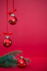 Red Christmas baubles and fir branches on a festive red background. Selective focus with blurred hanging ornaments and large copy space for holiday cards, greetings and seasonal advertising. © ольга дубровная