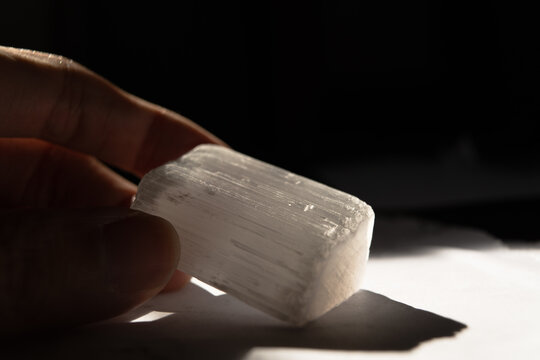 Hand Holding Selenite Crystal for Spirituality and Energy Healing in Dark Moody background