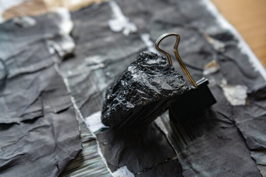 Tumbled Tourmaline Rock for Negative Energy Protection in Spiritual Way Photographed in Industrial Photography Style Standing with Support of Metal Binder Clip