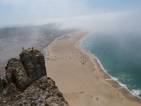 View over high cliff of Praia do Norte in Nazar&eacute; Portugal beach with fog rolling in