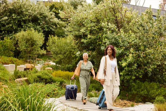 Two women carry suitcases