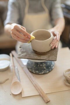 Hands shaping a handmade clay cup in pottery workshop