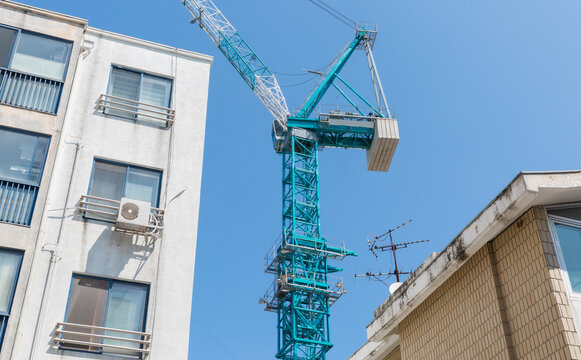 Blue Construction Tower Crane Beside Residential Building and Sky