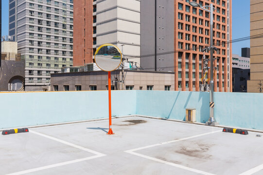 Rooftop Parking Lot with Traffic Mirror and Modern Buildings
