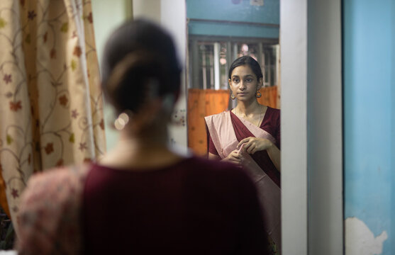 Young Indian woman wearing sari & standing in front of dressing table