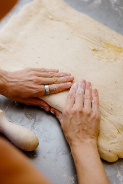 Anonymous woman's hands kneading cinnamon rolls on a quiet morning.