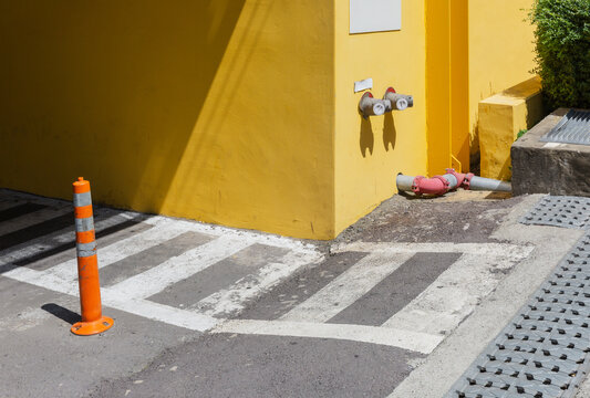 Bright Yellow Building Wall with Crosswalk and Orange Traffic Cone