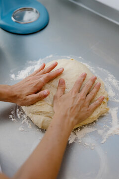 Female hands kneading fresh dough in a modern kitchen.