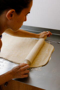 Woman using a wooden rolling pin to roll out baking dough