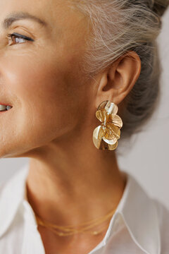 Woman wearing gold floral earrings and delicate necklaces