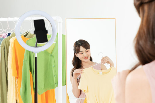 Woman hosting a live fashion sale and trying on clothes in front of a mirror