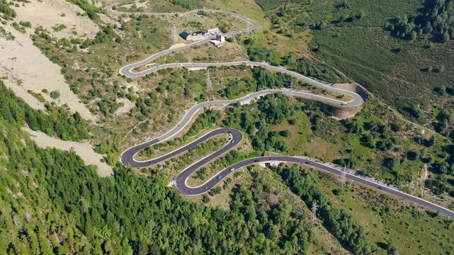 Aerial view of cars driving along winding S-curves on C-28 mountain road to Baqueira Beret during summer road trip, Spain