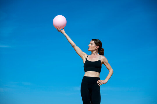 Woman Balancing a Pink Exercise Ball Outdoors