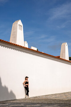 Woman in Sportswear Leaning Against White Wall