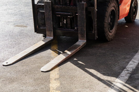 Forklift forks extend from a carriage beside the front tires of an industrial truck, showing pallet handling attachments used for moving equipment and goods around a rental yard