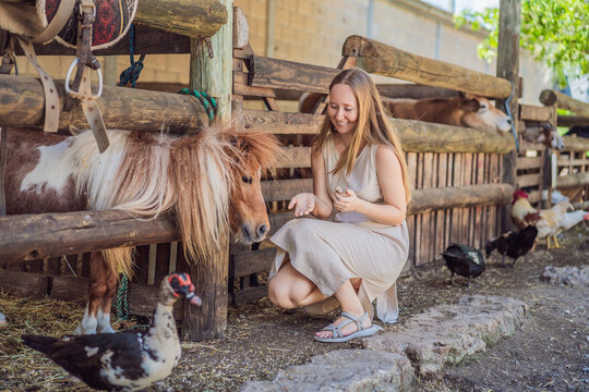 Smiling woman enjoys a pony encounter with a duck nearby. Joy and connection during a farm animal encounter.