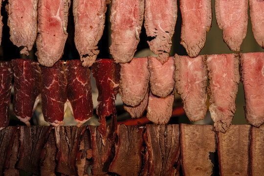 Variety of traditional smoked meats and artisanal sausages displayed on a market food stand counter.