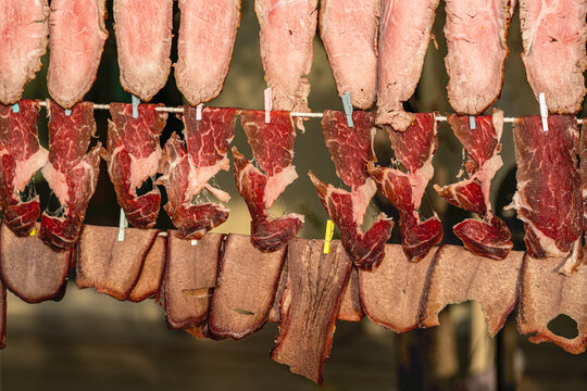 Variety of traditional smoked meats and artisanal sausages displayed on a market food stand counter.