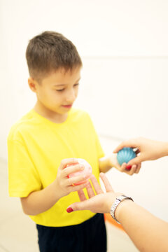 School age child participates in a sensory motor exercise with a therapist using textured therapy balls, developing hand coordination, motor planning and sensory processing skills.