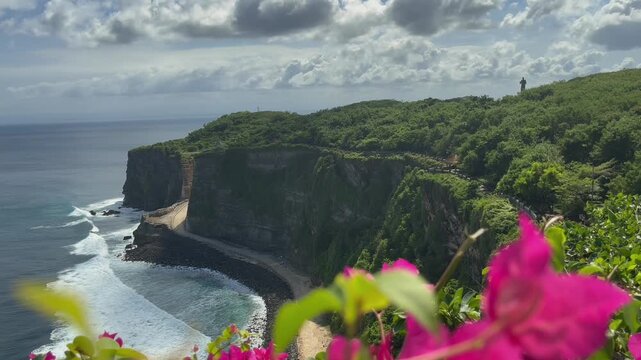 Uluwatu sea cliff with blurred pink bougainvillea foreground Bali.